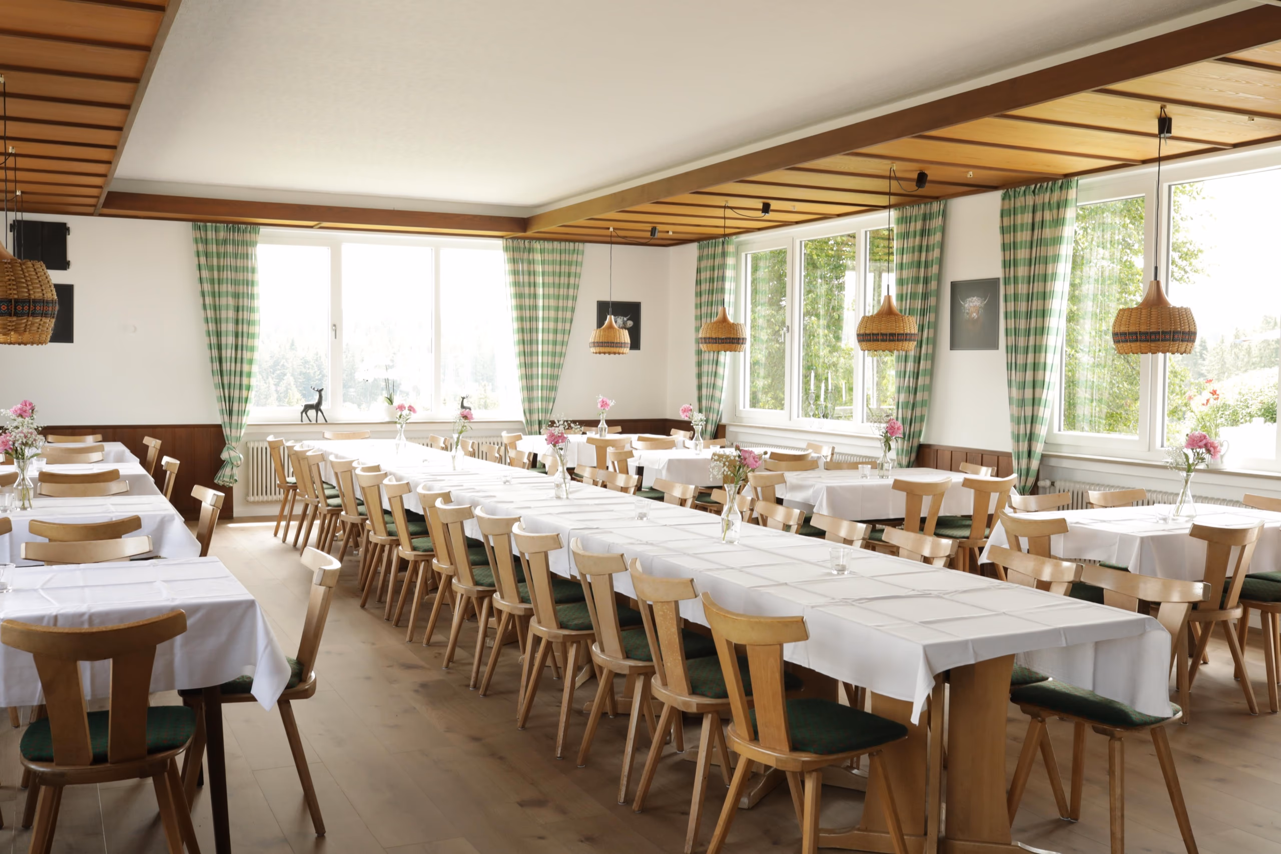 Heller Festsaal mit Blumenschmuck und Blick ins Grüne